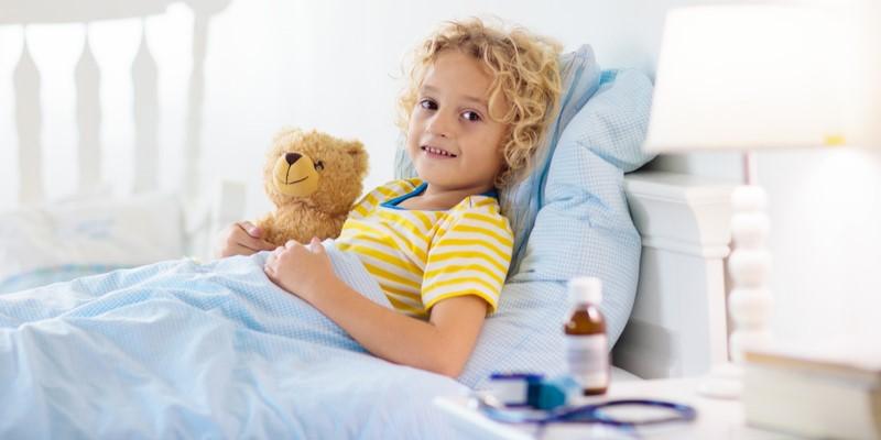 grypa u dzieci - zdjęcie przedstawia dziecko leżące w łóżku, trzymające przytulankę